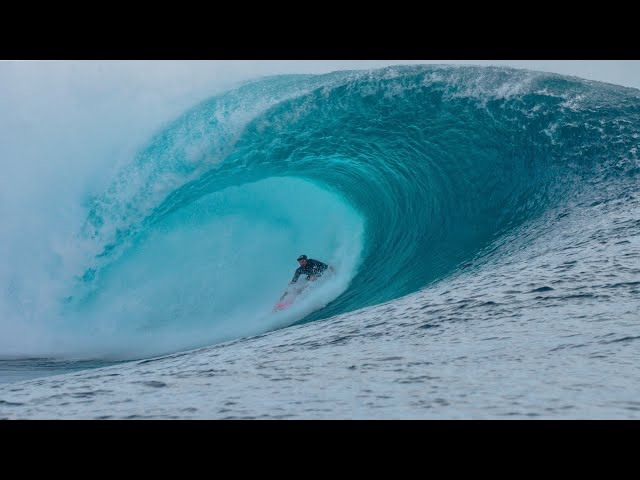 Surfer riding inside a large turquoise barrel wave